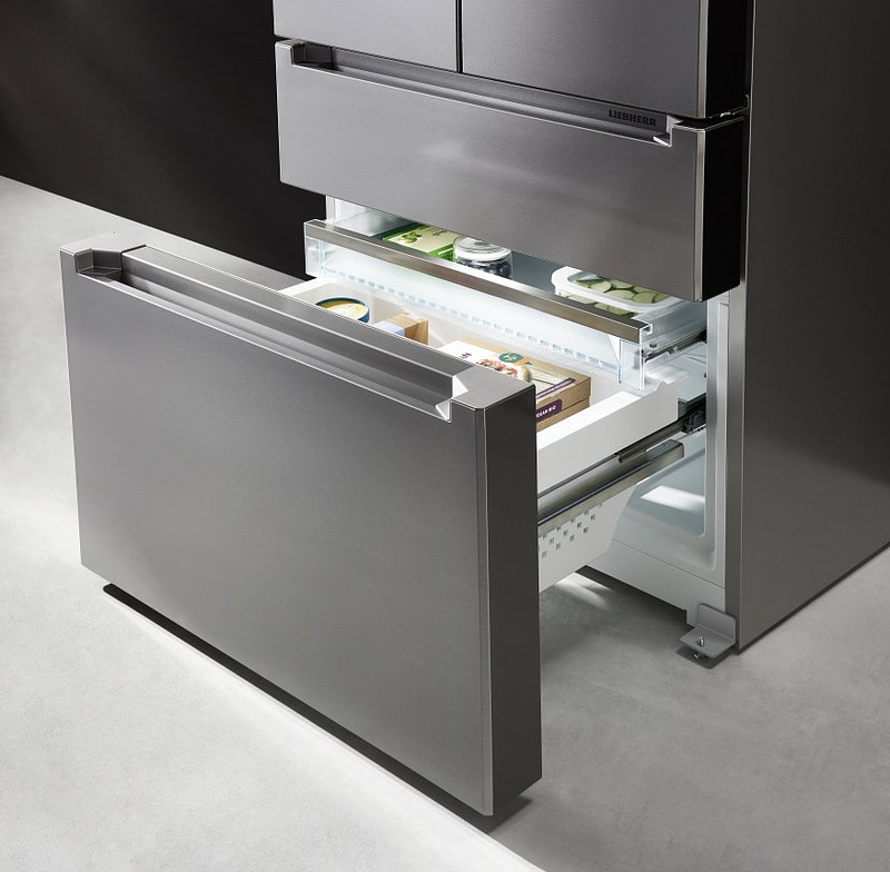 Le réfrigérateur LIEBHERR MBSDDI9524-20 en acier inoxydable se distingue par son design moderne et son tiroir de congélation inférieur ouvert, qui laisse entrevoir les aliments congelés à l'intérieur.