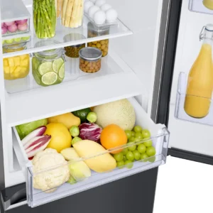Ouvrez le réfrigérateur SAMSUNG RB34C602EB1 pour découvrir des œufs, des bocaux, des tranches de citron vert, du jus de fruits et un tiroir rempli d'un assortiment de fruits et légumes : son intérieur spacieux permet de conserver tous vos aliments au frais et bien rangés.
