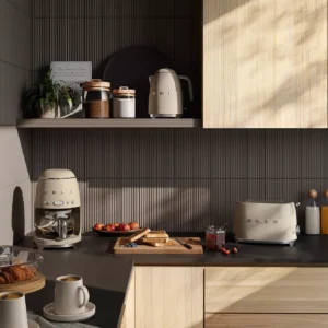 Cuisine moderne avec un grille-pain SMEG TSF01CHMEU beige, des toasts, des fruits et du café posés sur un plan de travail foncé, baignés par la douce lumière du soleil.