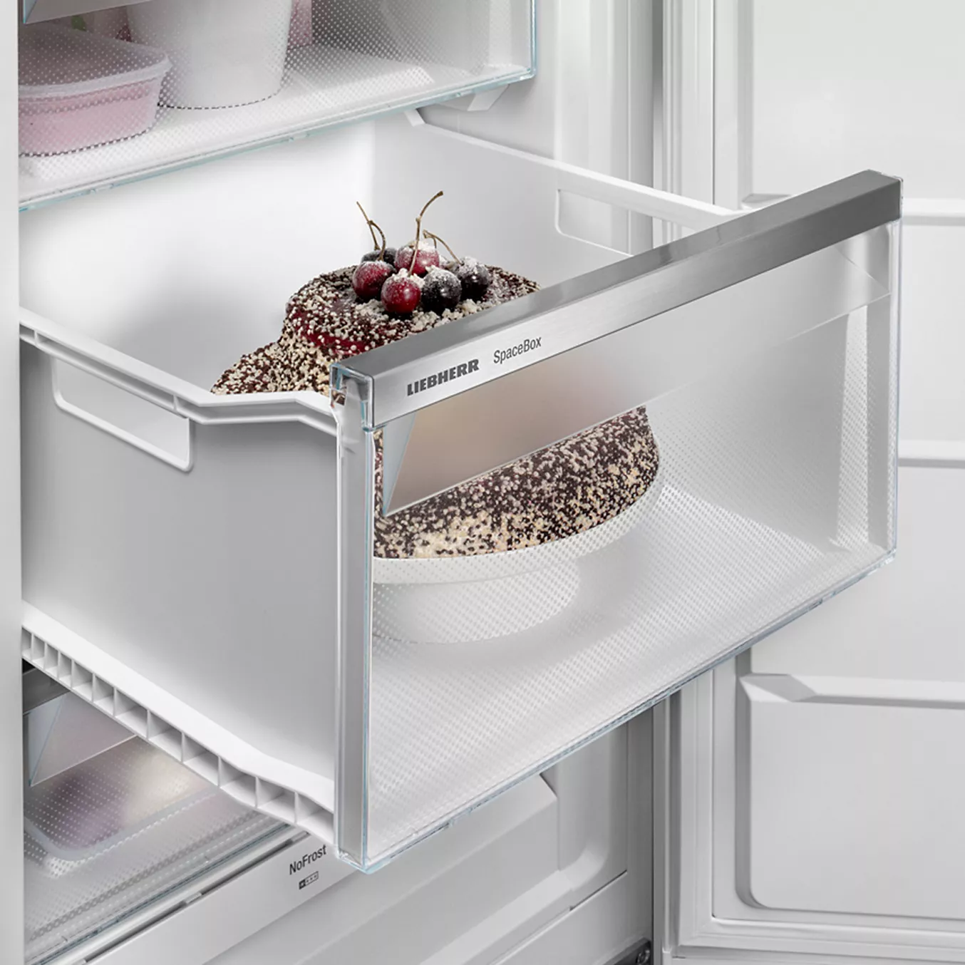 Un gâteau au chocolat garni de fruits rouges trône dans un tiroir de congélateur LIEBHERR FNE5016-20 ouvert, portant l'étiquette « SpaceBox », ce qui témoigne de la fiabilité de ce modèle.