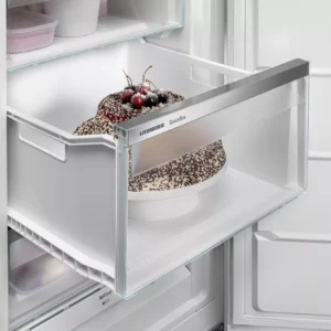 Un délicieux gâteau au chocolat garni de cerises repose dans un tiroir de congélateur SpaceBox ouvert, mettant en valeur les capacités de conservation fiables du modèle LIEBHERR FNE5217-20.