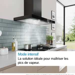 Une cuisine moderne où l'on aperçoit la hotte noire DWB97DN installée au-dessus d'une casserole fumante posée sur la cuisinière, tandis que la lumière du soleil pénètre à flots par la fenêtre.