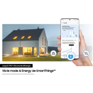 À la tombée de la nuit, une main tient un smartphone sur lequel s'affiche une application de gestion énergétique, devant une maison moderne illuminée, illustrant ainsi l'intégration parfaite avec des appareils électroménagers tels que le réfrigérateur SAMSUNG RB50DG601ES9, pour une gestion efficace de la maison.