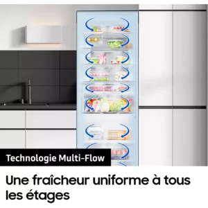 Le réfrigérateur SAMSUNG RB50DG601ES9, rempli d'aliments et doté de flèches indiquant la circulation de l'air, est présenté, porte ouverte, dans une cuisine moderne blanche.