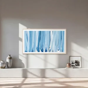 Cette pièce minimaliste est agrémentée d'un grand tableau abstrait bleu, de vases en céramique et d'une photo encadrée posée sur un banc en béton. L'ensemble est sublimé par le téléviseur SAMSUNG TQ65LS03HW, qui allie à la perfection technologie et design moderne.