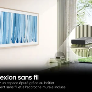 Un téléviseur SAMSUNG TQ65LS03HW est élégamment fixé au mur, accompagné d'un boîtier de connexion sans fil posé sur une table, dans une pièce au style contemporain dotée d'une grande fenêtre donnant sur un paysage verdoyant.