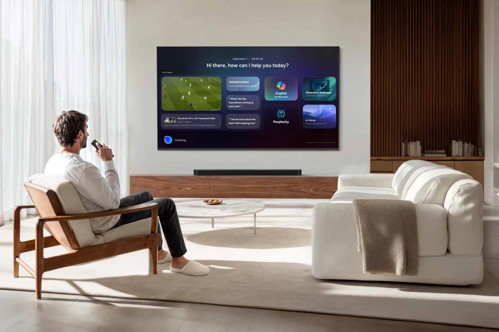 Un homme est assis sur un canapé, une télécommande à la main, et regarde son téléviseur SAMSUNG TU50M74H qui affiche plusieurs applications, dans un salon moderne.