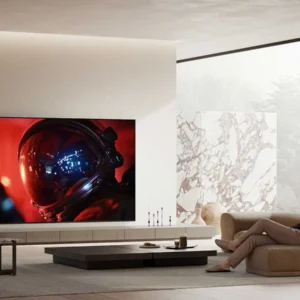 Un homme se détend sur un canapé dans un salon moderne, en regardant un film de science-fiction mettant en scène un astronaute sur le grand téléviseur SONY K-65XR95M2 True RGB, profitant d'une expérience visuelle immersive optimisée par sa technologie avancée True RGB.