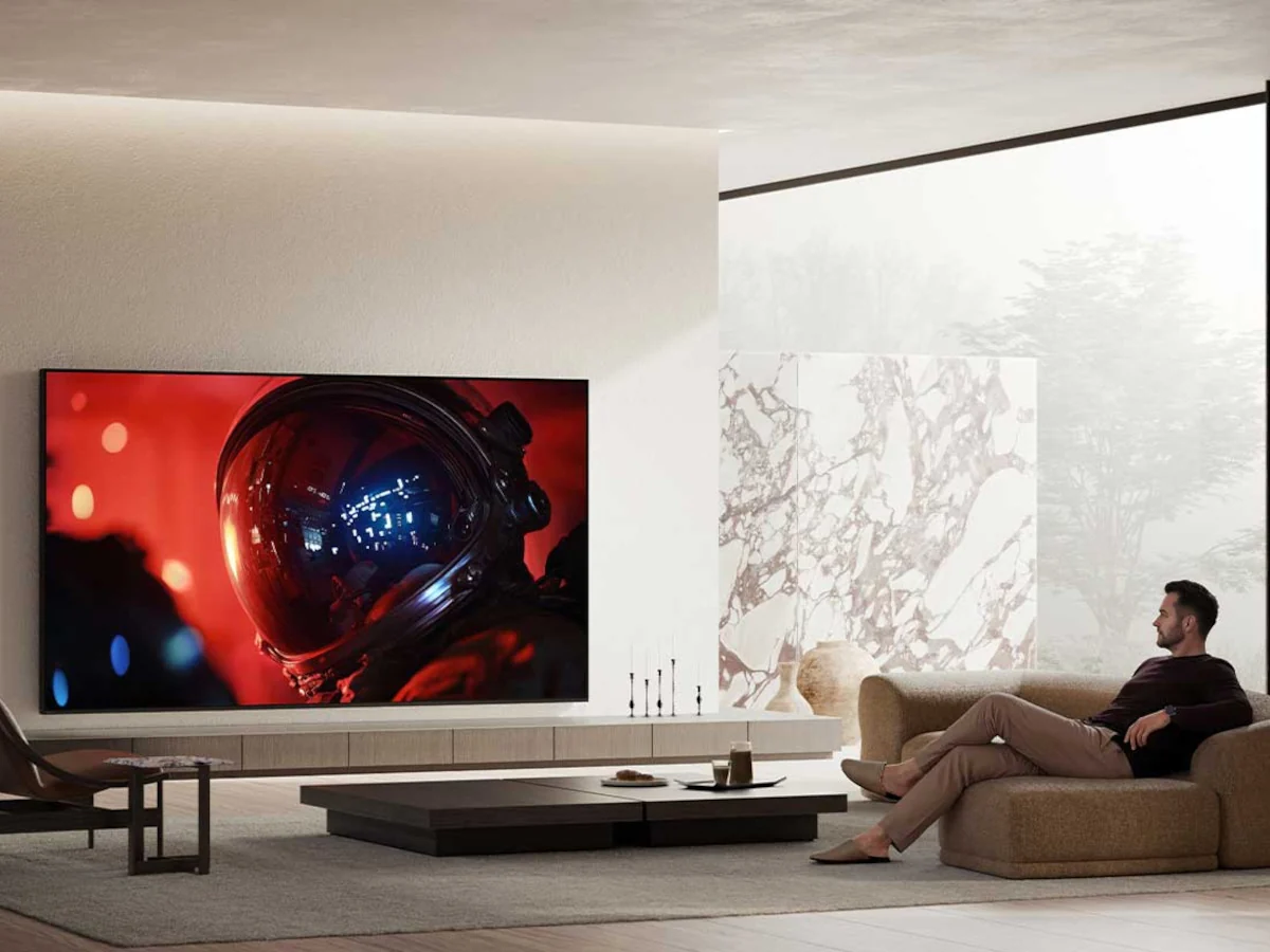 Un homme se détend sur un canapé en regardant un film de science-fiction mettant en scène un astronaute sur le grand téléviseur SONY K-75XR95M2 True RGB fixé au mur, et apprécie les images éclatantes offertes par sa technologie avancée True RGB.