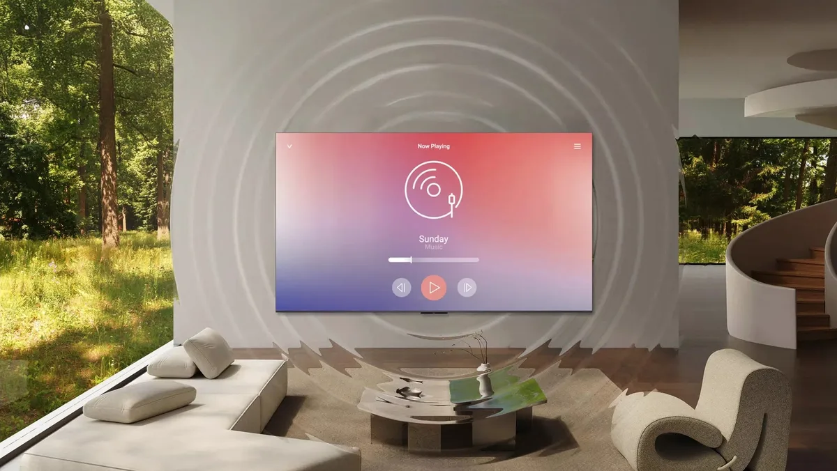 Un salon moderne équipé d'un téléviseur TCL 65C8L fixé au mur, sur lequel s'affiche la lecture musicale accompagnée d'une visualisation des ondes sonores.