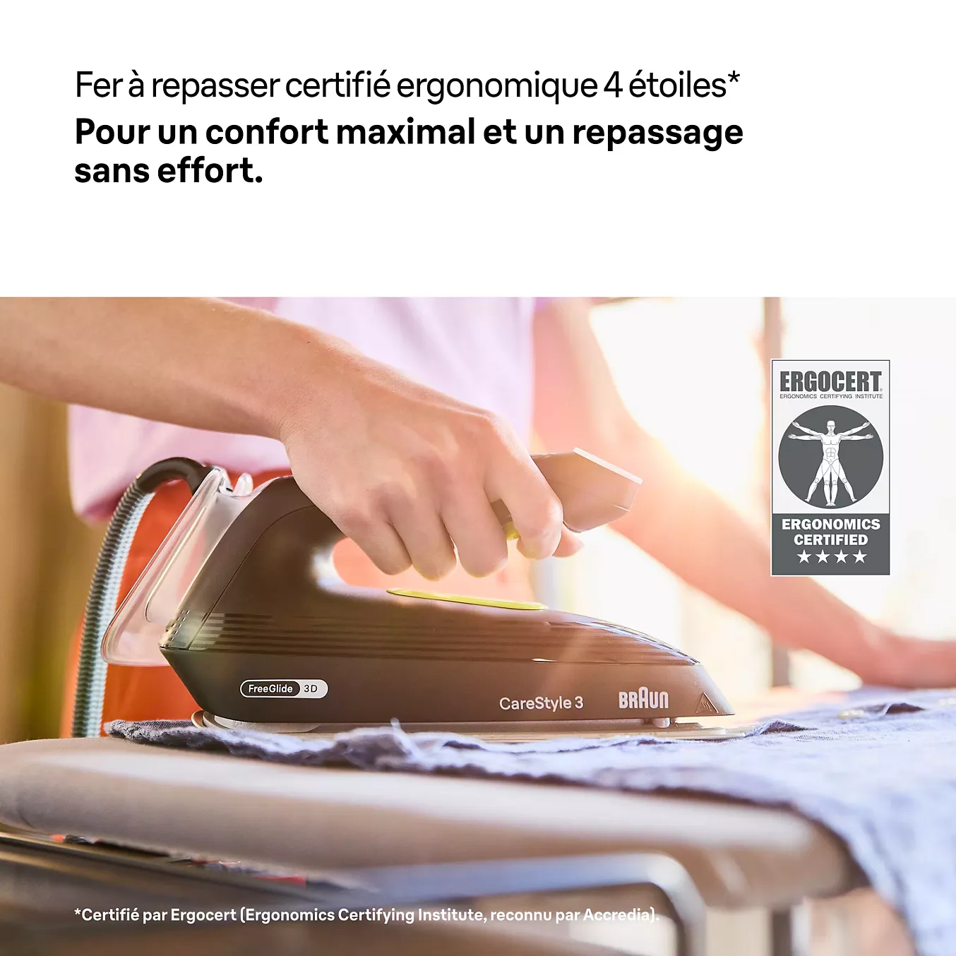 Une personne repasse une chemise à l'aide du fer à vapeur BRAUN IS3257BK, qui porte un label de certification ergonomique.
