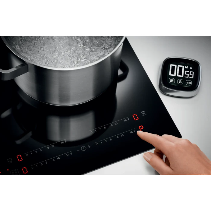 Une main règle la plaque à induction ELECTROLUX EIV63343 (Copier) ; une casserole est en train de bouillir tandis que le minuteur numérique indique qu'il reste 59 secondes.