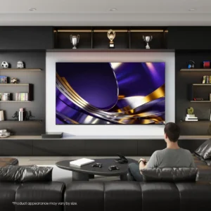 Une personne est assise sur un canapé dans un salon moderne décoré de trophées sportifs, en train de regarder un programme sur un téléviseur HISENSE 55U7S PRO.