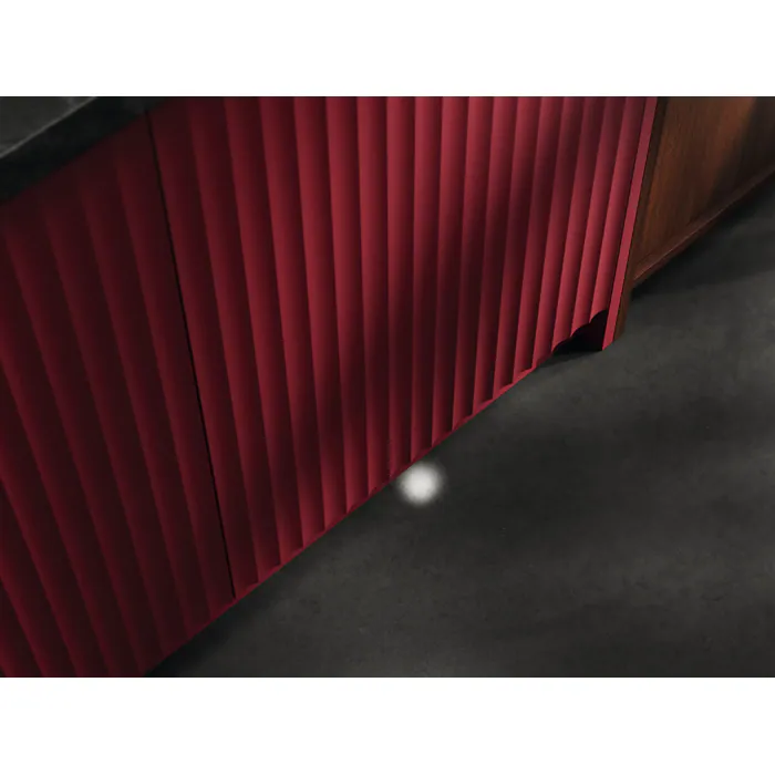 Armoire ELECTROLUX E62LB202S rouge rainurée, avec une petite lumière ronde blanche ou un reflet visible sur le sol gris foncé devant elle.