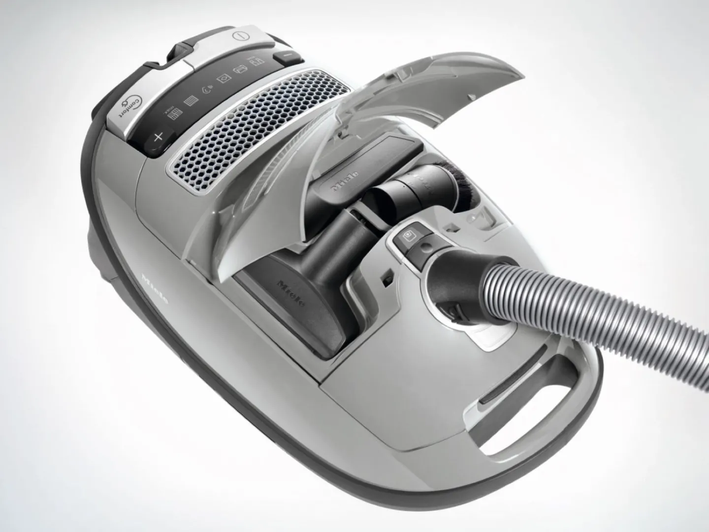 L'aspirateur-traîneau Miele GUARD M1 SILENCE, présenté ici en gris avec son couvercle supérieur ouvert, permet de ranger soigneusement les accessoires dans son compartiment pour une organisation pratique et intègre la technologie innovante SILENCE pour un fonctionnement silencieux.