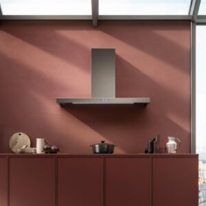 Cuisine moderne avec des placards rouges, une casserole sur la cuisinière et, au-dessus, une hotte FALMEC PLANEP1430 en acier inoxydable aux lignes épurées.